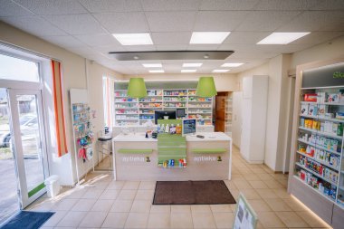 Ilukste, Letonya - 10 Eylül 2024 - Tezgahları, ilaç rafları ve ürünleri parlak ışık altında sergilenen modern bir eczanenin geniş açılı görünümü.