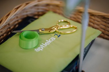 Ilukste, Letonya - 10 Eylül 2024 - Altın makas ve yeşil kurdele sepetin içinde, sığ bir alan derinliğinde yeşil bir torba.