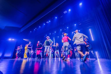 Valmiera, Letonya - 8 Şubat 2025 - 90 'ların partisi. Eskilerden esinlenilmiş bir grup sanatçı neon ışıkları altında sahnede dans ediyor, neşe, güven ve enerji ifade ediyorlar..