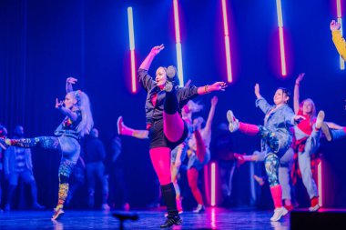 Valmiera, Letonya - 8 Şubat 2025 - 90 'ların partisi. Eskilerden esinlenilmiş bir grup sanatçı neon ışıkları altında sahnede dans ediyor, neşe, güven ve enerji ifade ediyorlar..