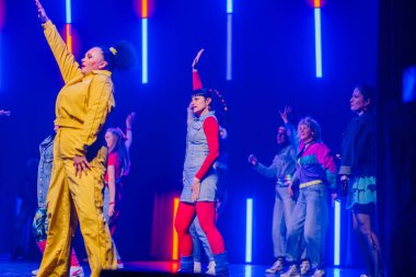 Valmiera, Letonya - 8 Şubat 2025 - 90 'ların partisi. Eskilerden esinlenilmiş bir grup sanatçı neon ışıkları altında sahnede dans ediyor, neşe, güven ve enerji ifade ediyorlar..