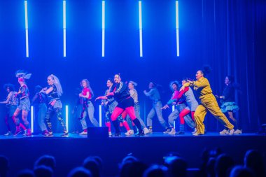 Valmiera, Letonya - 8 Şubat 2025 - 90 'ların partisi. Eskilerden esinlenilmiş bir grup sanatçı neon ışıkları altında sahnede dans ediyor, neşe, güven ve enerji ifade ediyorlar..