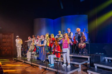 Valmiera, Letonya - 8 Şubat 2025 - Müzisyenler ve şarkıcıların sahne aldığı canlı bir parti performansı, retro kıyafetler, güneş gözlükleri ve geleneksel ve modern enstrümanların bir karışımı
