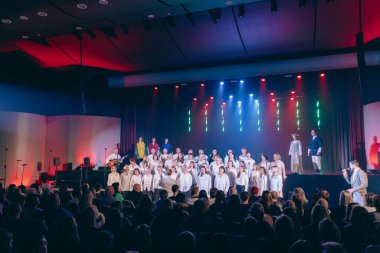 Valmiera, Letonya - 8 Şubat 2025 - 90 'lı yılların partisinde renkli ışıklar, izleyiciler, Baltık bayrakları ve geleneksel kostümlerle canlı bir atmosfer yaratan koro gösterisi