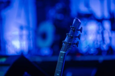 Valmiera, Letonya - 29 Aralık 2024 - Sahnede mavi ışıklı bir bas gitar başlığı, arka planda bulanık davullar ve bir konser atmosferi.