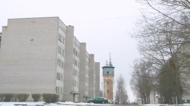 Seda, Letonya - 12 Şubat 2025 - Arka planda eski bir su kulesi bulunan ve şimdi iletişim antenleriyle donatılmış Sovyet döneminden kalma tuğladan bir apartman dairesi..