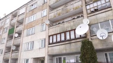 Seda, Letonya - 12 Şubat 2025 - Balkonunda uydu antenleri olan yıpranmış bir Sovyet döneminden kalma apartman. Çürümüş ve yıpranmış gibi görünüyor, çürüme belirtileri gösteriyor..