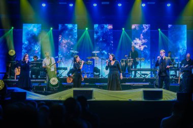 Valmiera, Letonya - 29 Aralık 2024 - Yamaha etkinliği. Şarkıcıların ve müzisyenlerin sahne aldığı canlı bir konser renkli ışıklandırma, dijital ekranlar ve seyircilerin önünde enerjik bir atmosfer..