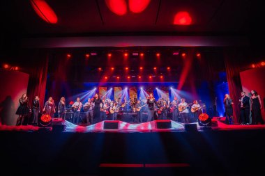 Valmiera, Letonya - 29 Aralık 2024 - Büyük bir grup müzisyen ve şarkıcı, gitarlar, vokalistler ve dramatik ışıklandırma efektlerinin yer aldığı bir Yamaha etkinliğinde parlak bir sahnede gösteri yaptılar..