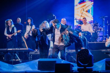 Valmiera, Letonya - 29 Aralık 2024 - Yamaha 'da bir konserin sonunda arkada müzisyenlerin olduğu canlı performanslar sergiliyor. Sahnede minnettarlık ve takdir anı..