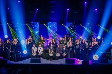 Valmiera, Letonya - 29 Aralık 2024 - Bir Yamaha etkinliğinde canlı bir performans, renkli ışıklarla aydınlatılmış bir sahnede çeşitli şarkıcı, davulcu ve gitaristlerin yer aldığı.