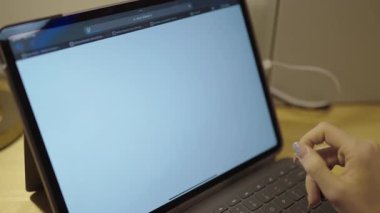 Bir kişi çevrimiçi bir okul programını kontrol etmek için bir klavye ile dokunmatik ekran tableti kullanıyor. Ekranda konular ve görevler bir eğitim portalında gösterilir.