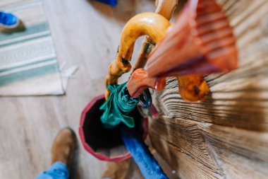 Lubana, Letonya - 15 Şubat 2025 - Tahta bir baston, silah saplı yeşil bir şemsiye ve kırsal ahşap bir tutacağa depolanmış mavi bir şemsiye.