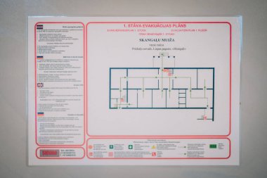 Cesis, Letonya - 17 Şubat 2025 - Skangali Malikanesi 'nin birinci katı için tahliye planı, acil çıkış yolları, yangın güvenliği talimatları ve birçok dilde semboller.