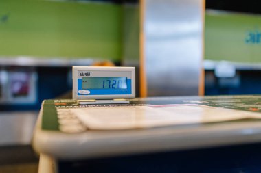 Riga, Latvia - February 22, 2025 - A digital luggage scale at an airport check-in counter displaying 17.2 kg. The background shows an airline counter with blurred branding and signage. clipart