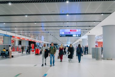 İstanbul, Türkiye - 22 Şubat 2025 - Gezginlerin yürüdüğü, bavul taşıdığı ve nakil masalarını kontrol ettiği yoğun bir havaalanı terminali. Genel tabelalar uluslararası ve yerli aktarımlara rehberlik ediyor.