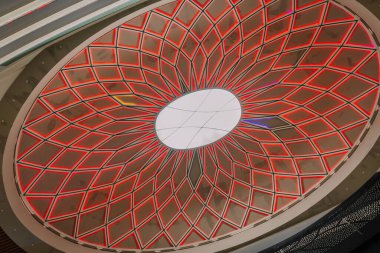 Kırmızı LED ışıklandırmalı karmaşık geometrik tavan kubbesi ve modern mimari tasarım ve simetri sergilenen merkezi tavan penceresi..