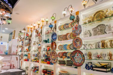 Serik, Türkiye - 24 Şubat 2025 - Karmaşık el yapımı eşyalarla dolu geleneksel bir hediyelik eşya dükkanında renkli Türk seramikleri, mozaik lambaları ve dekoratif hediyelik eşya sergisi.