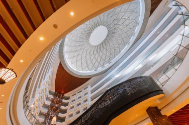 Serik, Türkiye - 24 Şubat 2025 - çarpıcı bir geometrik cam kubbe tavanı, zarif balkonları ve karmaşık tasarımı olan şık siyah bir merdiveni olan modern otel iç mimarisi.