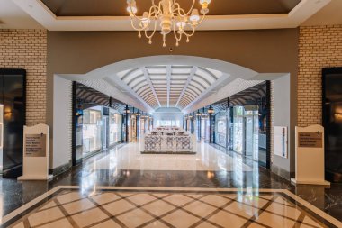 Serik, Türkiye - 24 Şubat 2025 - Lüks bir otelde lüks bir alışveriş salonu, parkeleri, butik mağazaları, kemerli tavanları ve dekoratif ışıklandırması olan.