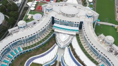 Serik, Türkiye - 28 Şubat 2025 - Modern mimarisi, kıvrımlı balkonları, çatı havuzları, yeşil alanlar ve eğlence tesisleri olan lüks bir otelin havadan görünüşü.