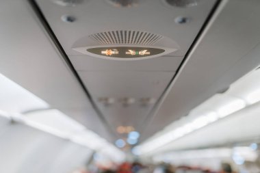 Riga, Letonya - Mart 01, 2025 - Bir uçak kabininde sigara içilmez ve emniyet kemeri işaretleri takılmaz. Güvenlik göstergeleri üstteki yolcu panelinde gösteriliyor.