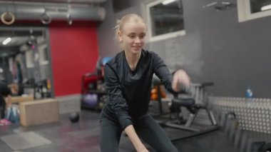 Valmiera, Letonya - 4 Şubat 2025 - odaklanmış bir kadın spor salonunda savaş halatlarıyla egzersiz yapar, dayanıklılık ve dayanıklılık sağlar. Arka planda çalışan başka biri daha var..