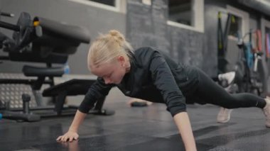 Valmiera, Letonya - 4 Şubat 2025 - Siyah spor kıyafetli genç bir kadın spor salonunda şınav çekiyor. Odaklanmış ve kararlı. Güçlü bir eğitim alıyor..