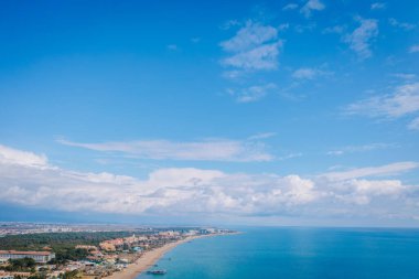 Serik, Türkiye - 28 Şubat 2025 - Parlak bir günde kumlu plajları, turkuaz denizi ve dağınık bulutlu engin mavi gökyüzü olan kıyı kenti manzarası.