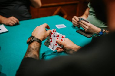 Belek, Türkiye - 22 Şubat 2025 - Poker masasında el ele oynayan oyuncuların yakın çekimi. Diğer oyuncular arka planda görülür, kart oyununda yer alırlar