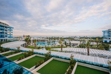 Modern mimarisi, palmiye ağaçları, havuzları ve gün batımı olan lüks bir sahil beldesi rahatlatıcı bir tatil atmosferi yaratıyor..