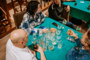 Belek, Türkiye - 22 Şubat 2025 - Boş bardaklar, içecekler ve abur cuburlarla dolu bir masada sosyalleşen bir grup insan, sıradan bir ortamda canlı bir atmosfer yaratıyor..