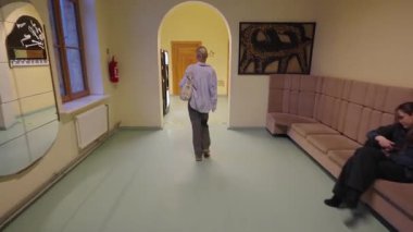 Valmiera, Letonya - 4 Şubat 2025 - çantalı bir kadın okul koridorundan sınıfın kapısına doğru yürüyor. Koridorda otomatlar, ahşap kapılar ve müzikal dekorasyonlar var..