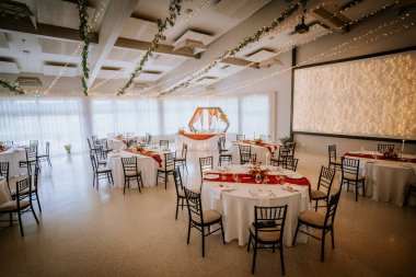 Koknese, Letonya - 26 Eylül 2023 - Süslü masalar, peri ışıkları ve çiçeklerle süslenmiş zarif düğün salonu, romantik ve şenlikli bir ortam yaratıyor..