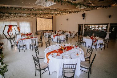 Koknese, Letonya - 26 Eylül 2023 - Süslü masalar, çiçek düzenlemeleri ve peri ışıklarıyla şık bir düğün salonu, romantik ve şenlikli bir ortam yaratıyor..