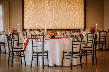 Koknese, Letonya - 26 Eylül 2023 - Zarif bir düğün resepsiyonu, masaları, çiçekli süslemeleri, mum ışığı ve sıcak peri ışıkları romantik bir ortam yaratıyor..