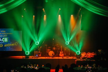 Valmiera, Letonya 29 Kasım 2024 - Yeşil spot ışıkları, müzik aletleri ve ACB logosunu gösteren büyük ekranlı bir ACB etkinliği için sahne seti. Mekanın şenlikli ve zarif bir atmosferi var..