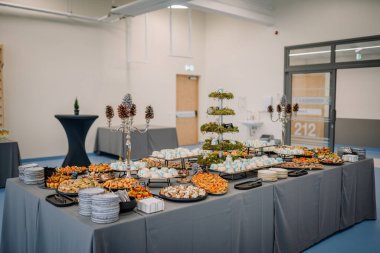 Valmiera, Letonya - 29 Kasım 2024 - Gurme aperatifleri, tatlılar ve bir rehabilitasyon merkezinde bir masada düzenlenen dekorasyonlar ile şık büfe.