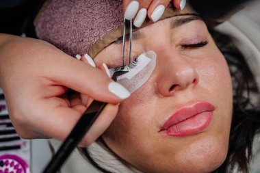 Yukarı bakan bir kadının gözünün yakın çekimi, yeni uygulanmış kirpik uzantılarını ve göz çevresindeki detaylı deri dokusunu vurguluyor.