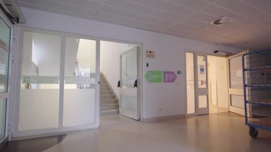 Valmiera, Letonya - 24 Mart 2025 - Hastane koridorunda merdiven girişi ve temiz iç aydınlatma ile annelik, jinekoloji ve nöroloji bölümlerini gösteren işaretler var.