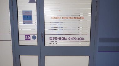 Valmiera, Letonya - 24 Mart 2025 - Bir ebe hastane koridorundaki otomatik kapılardan doğum koğuşuna girer..
