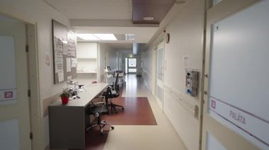 Valmiera, Letonya - 24 Mart 2025 - Hemşire istasyonu, tıbbi gereçleri, boş sandalyeleri ve temiz, modern bir iç mekanı olan parlak hastane koridoru.