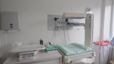 Valmiera, Letonya - 24 Mart 2025 - Bebek ölçeğine sahip modern yenidoğan bakım istasyonu, ısıtma yatağı, tıbbi ekipmanlar ve hastane odasındaki temiz beyaz çevre.