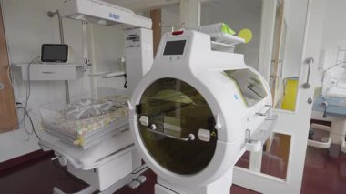 Valmiera, Letonya - 24 Mart 2025 Modern Yenidoğan Bakım Odası yüksek teknolojili kuluçka makineleri ve ısıtma üniteleri, dairesel bir kuvöz ve tıbbi ekipmanlı bebek yatağı.