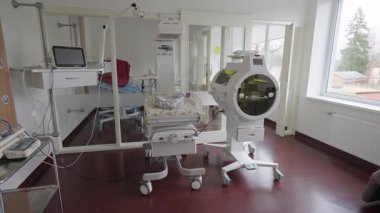 Valmiera, Letonya - 24 Mart 2025 - Gelişmiş kuluçka makineleri, bebek yatağı, monitörler ve bebek bakımı için tıbbi cihazları olan parlak yenidoğan hastane odası, hepsi tekerlekli birimlerde.