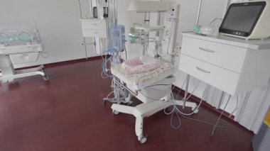 Valmiera, Letonya - 24 Mart 2025 - Gelişmiş tıbbi gereçleri ve hazırlanmış bir bebek bakım istasyonu bulunan, monitörler, kablolar ve yaşam destek cihazlarının yer aldığı yeni hastane odası.