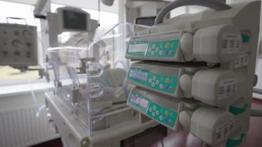 Valmiera, Letonya - 24 Mart 2025 - Yeni doğan bir bebeğe bakmak için bir hastane odasında kuluçka makinesi ve infüzyon pompaları da dahil olmak üzere yeni doğan yoğun bakım ekipmanlarının yakın görüntüsü.