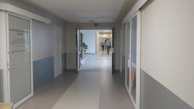 Valmiera, Letonya - 24 Mart 2025 - Kadın oturma alanı, kitap rafları ve ev bitkileriyle aydınlık bir hastane koridorunda yürür sakin ve misafirperver bir ortam yaratır..