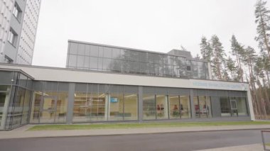 Valmiera, Letonya - 24 Mart 2025 - Çam ağaçlarıyla çevrili büyük camlı rehabilitasyon merkezi binası. Temiz dış görünüş klinik ve barışçıl bir çevreyi yansıtıyor..