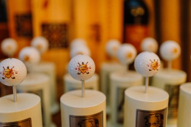 Riga, Letonya - 27 Mart 2025 - Rossini Golf topları ile yakın çekim golf kupaları ahşap tabanlarda, yumuşak ışıklandırma ile sıcak bir iç mekanda sergilenir